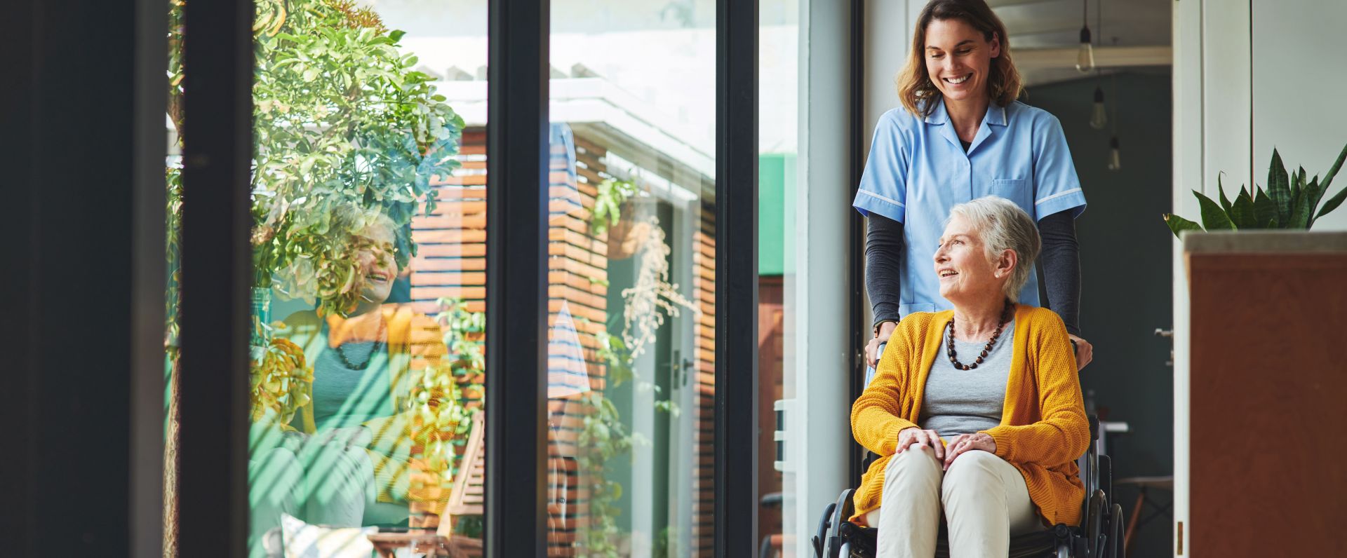 Eine Altenpflegerin kümmert sich um eine Dame im Rollstuhl
