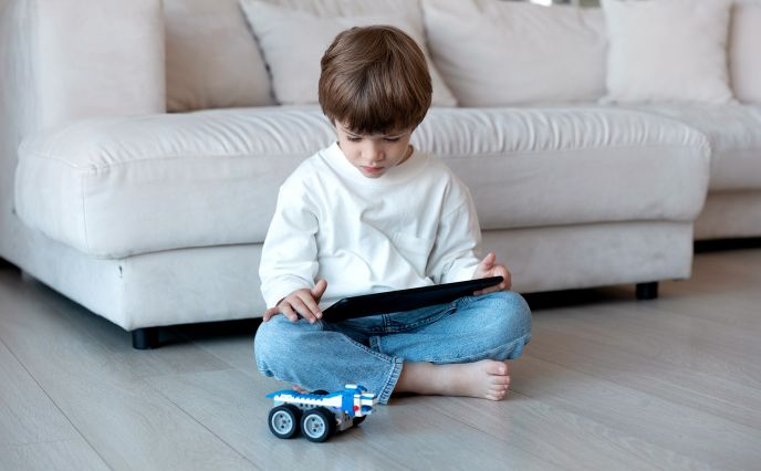 Kleines Kind nutzt Tablet als Fernbedienung für ein Roboterauto