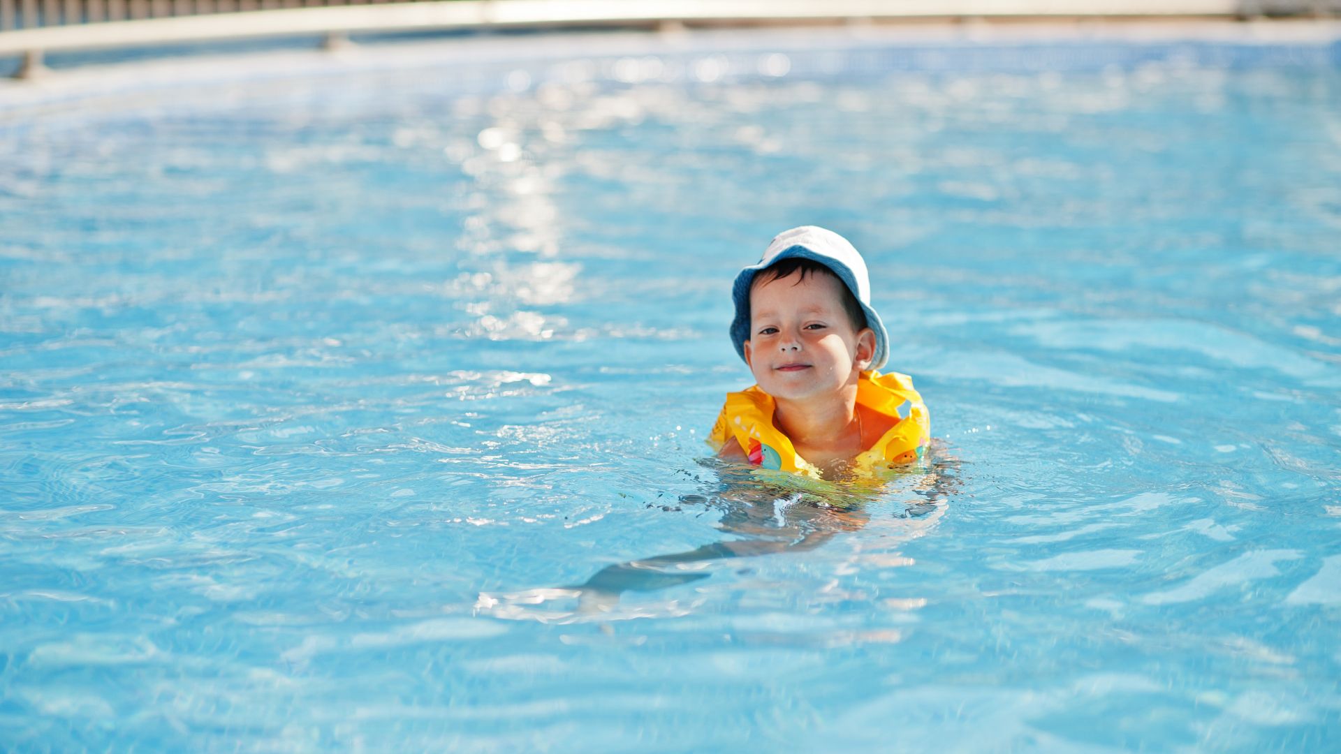 Kleiner Junge mit Schwimmflügeln im Wasser