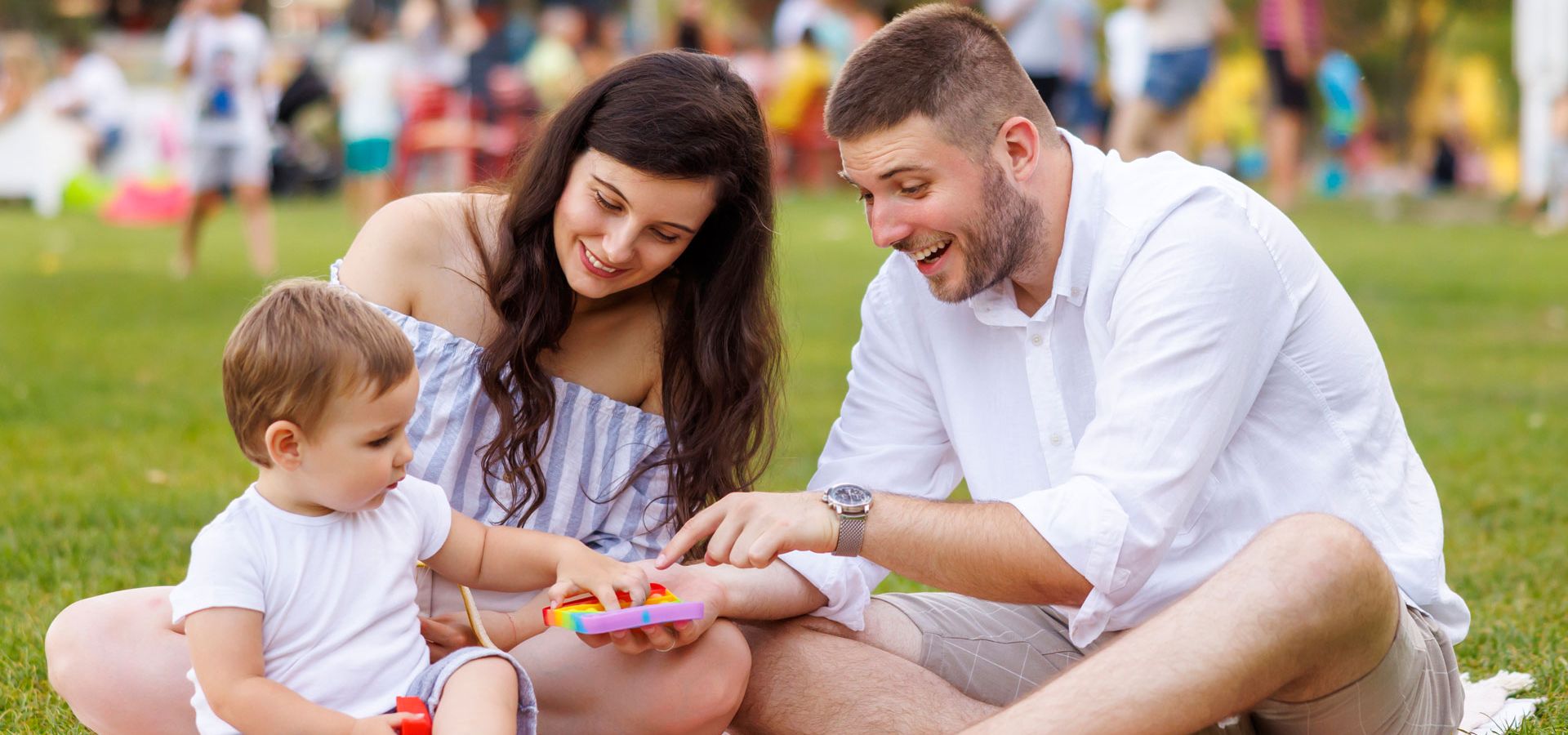 Zwei junge Eltern beim Picknick und spielen im Park