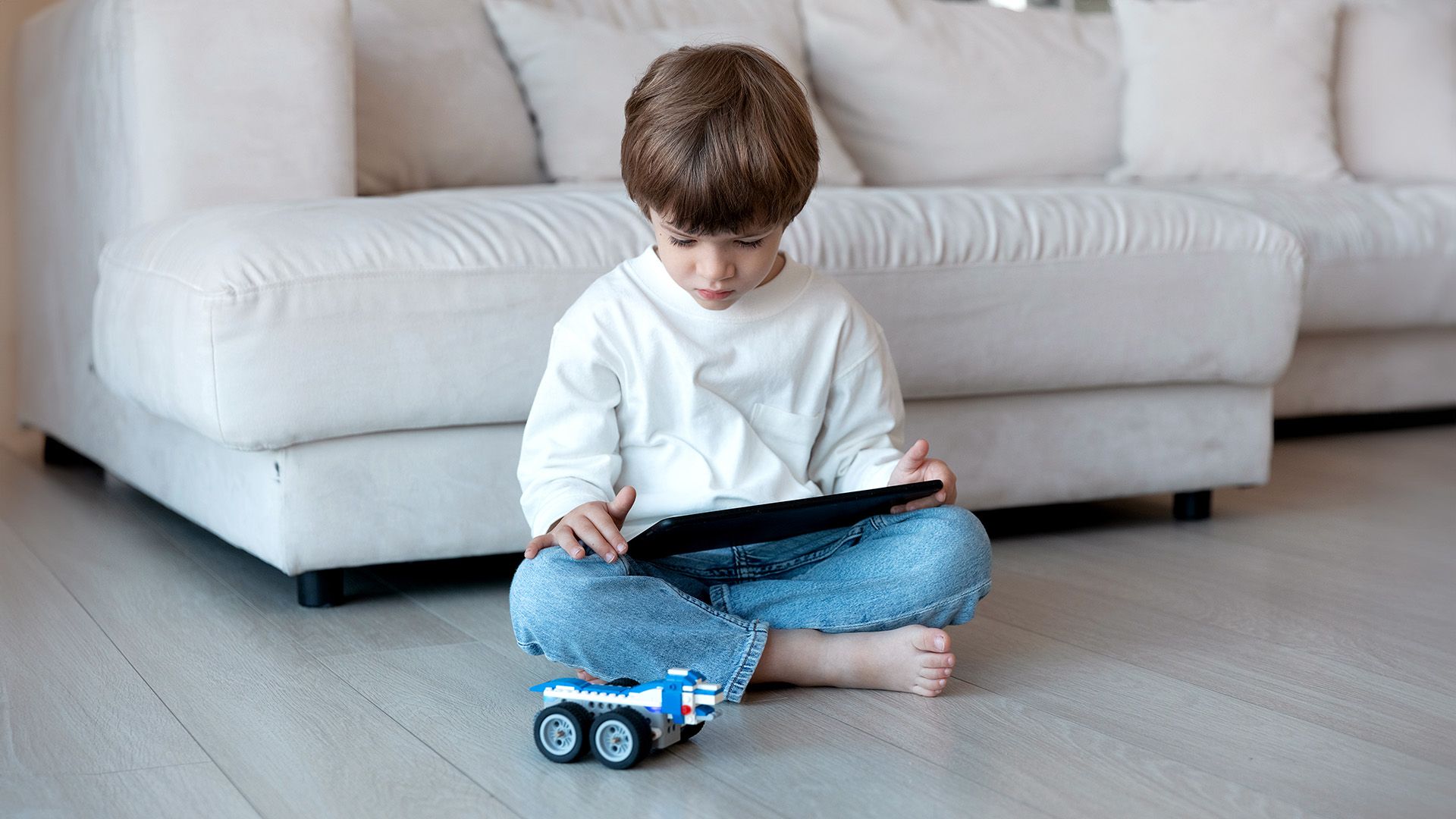 Kleines Kind nutzt Tablet als Fernbedienung für ein Roboterauto